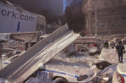 Ground zero on September 11, 2001, mid-day. Emergency vehicles of the first responders have been destroyed, and fires can be seen in the immediate area.